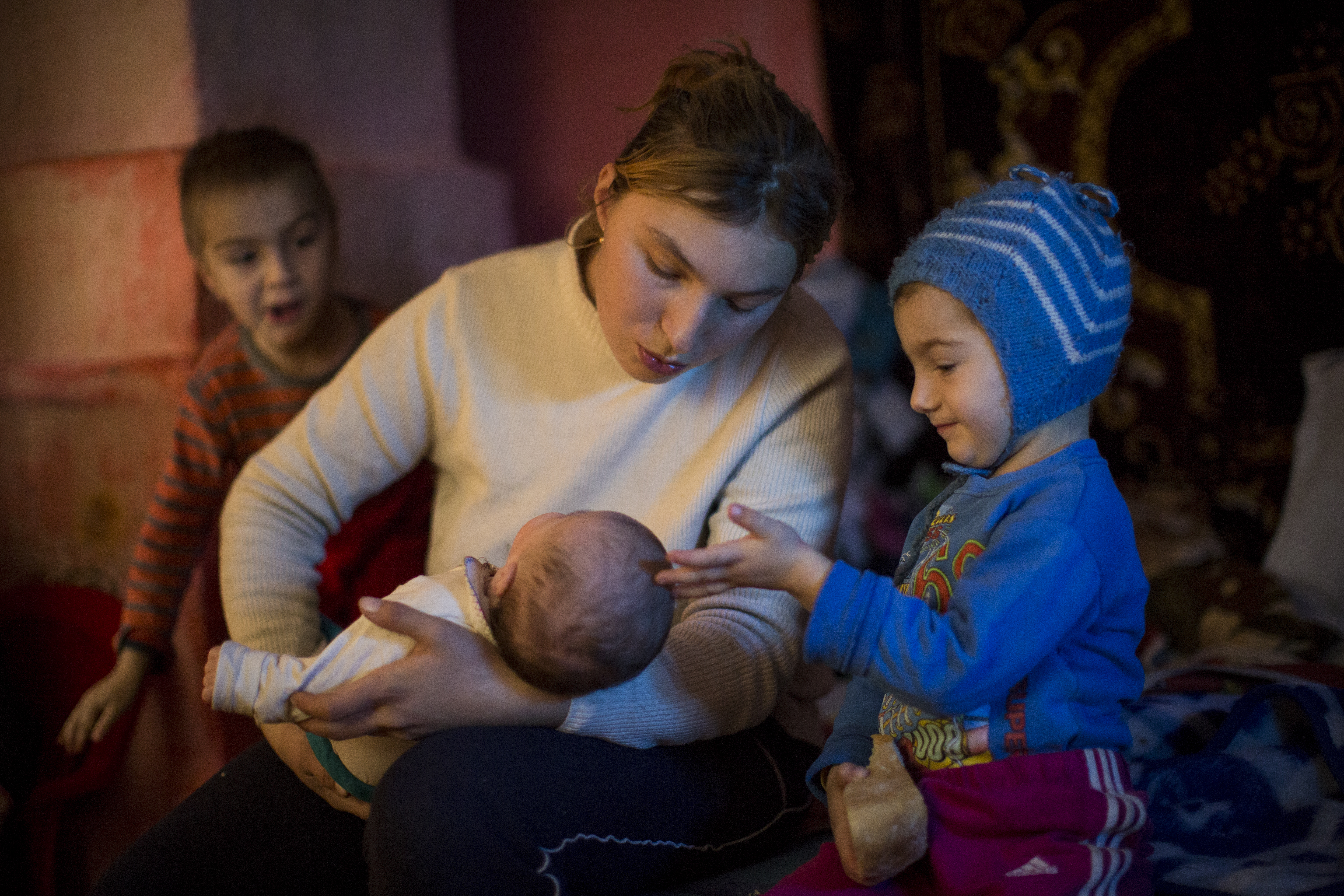 Mother holding baby alongside two other young children - in Romania