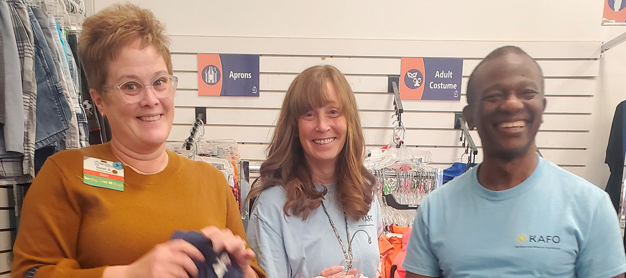 3 acquaintances smile together in clothing store