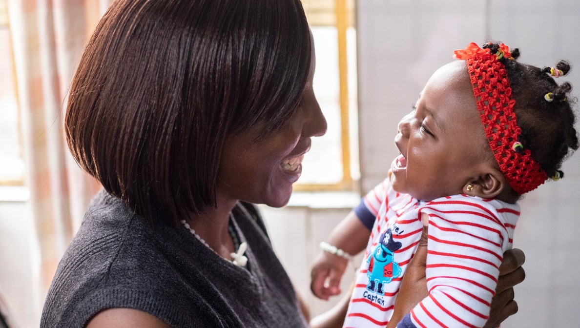 woman smiling and holding a smiling infant
