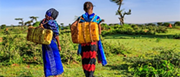 Young girls carrying water walking in nature
