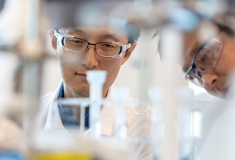 Two male scientists looking at beaker