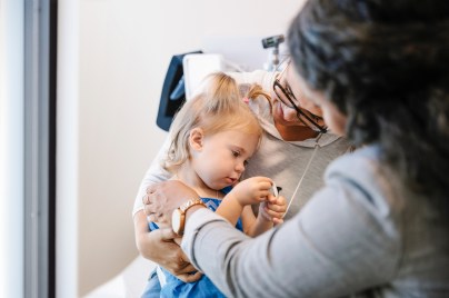 Young infant girl with doctor and parent