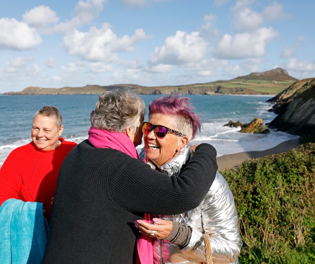 Two people embracing on a mountain with view of ocean