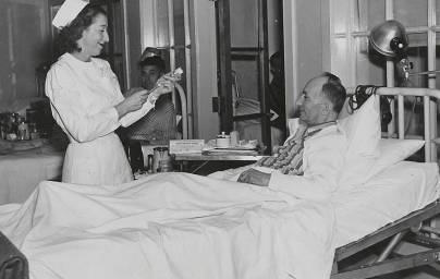 Nurse prepares syringe to give dose to patient in hospital bed
