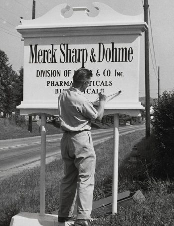 Man changes sign to read Merck Sharp & Dohme (MSD) [(headquartered in Rahway, New Jersey, U.S.)]