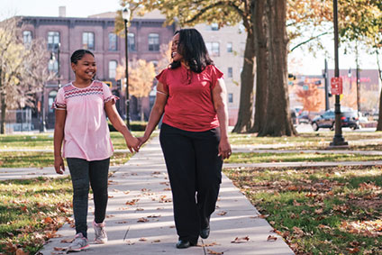 Denarra walking down the sidewalk with a child