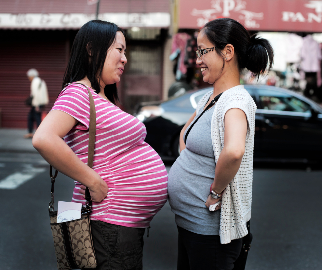 two pregnant women touching bellies