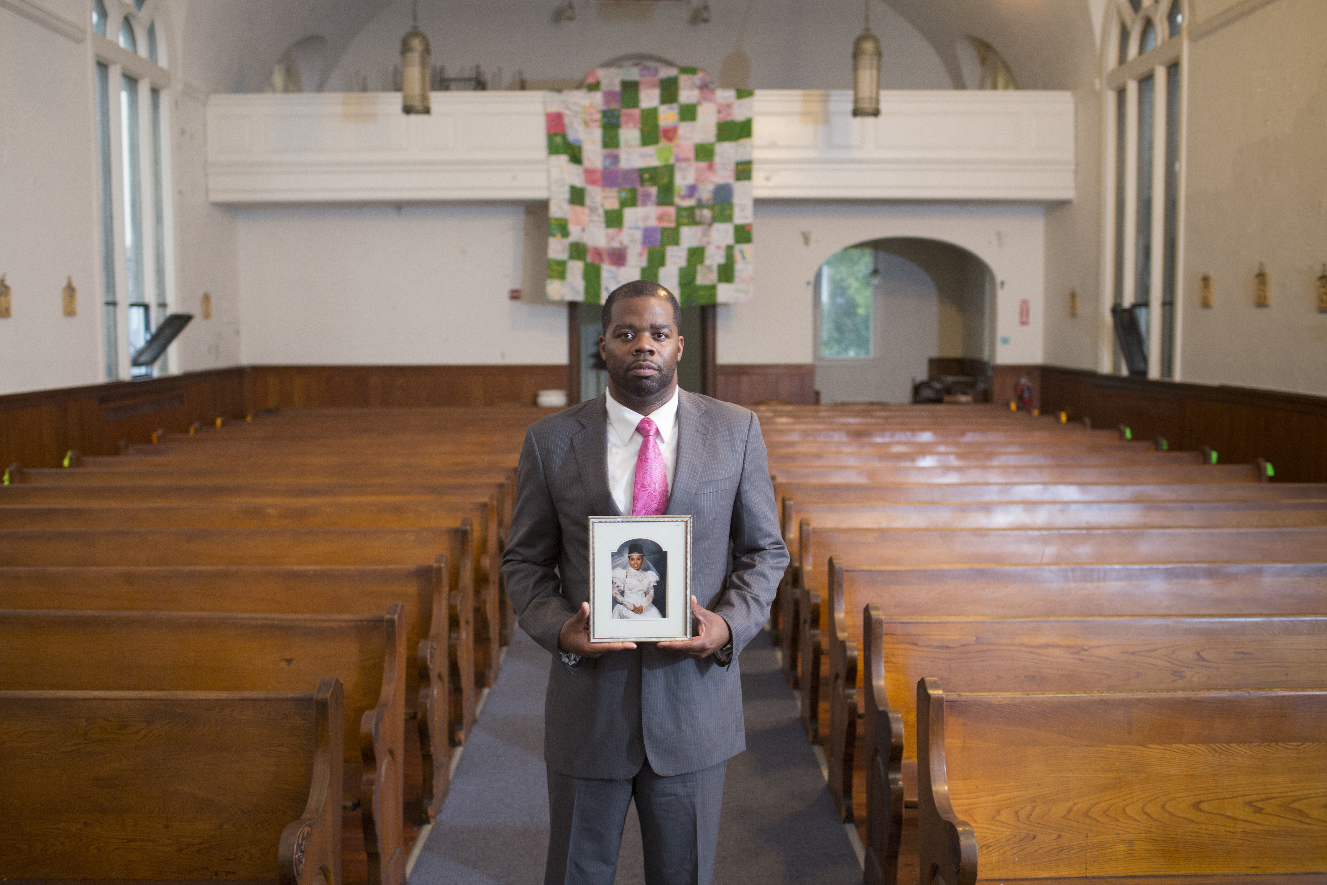 A man holding a picture of a loved one in a church