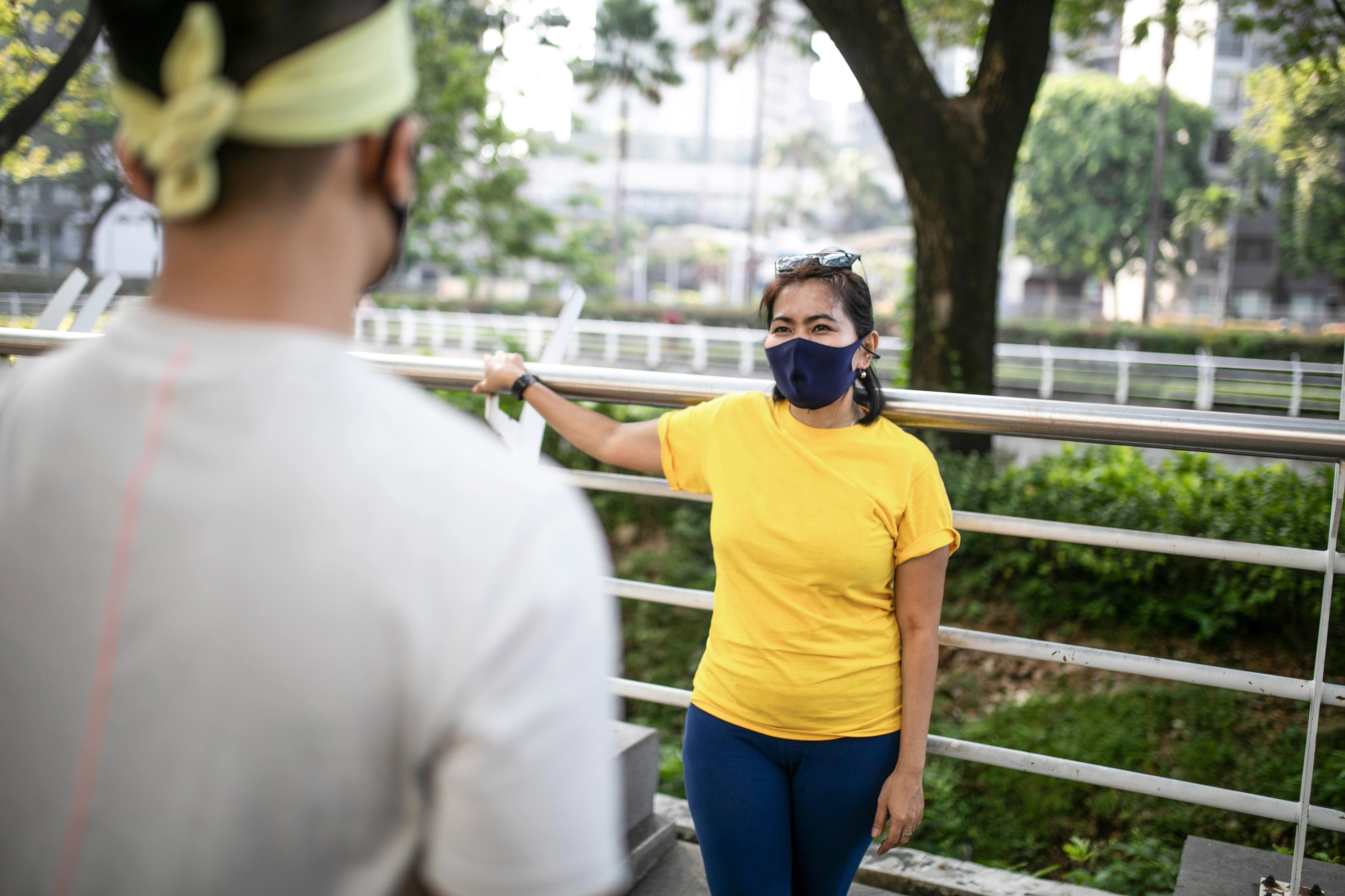 woman wearing a mask leaning against a railing