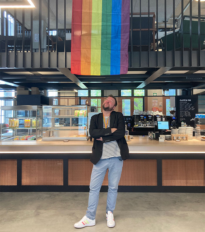 Lutz standing under a pride flag