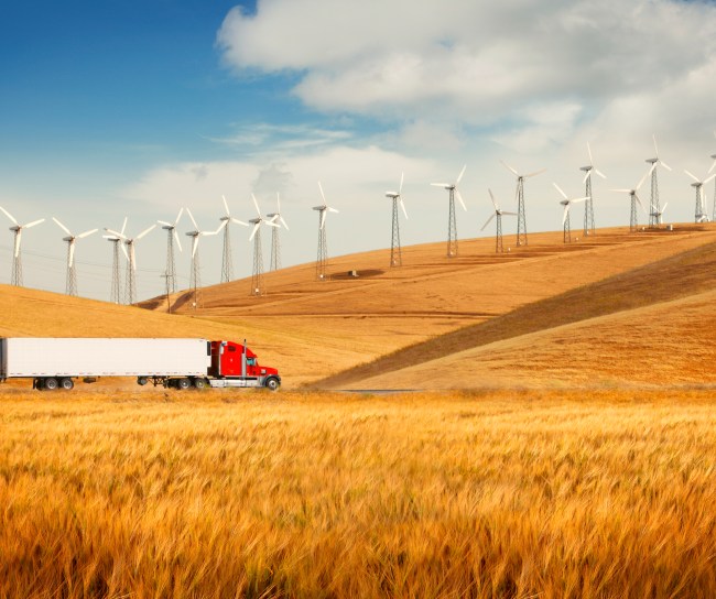 truck driving among fields with wind mills