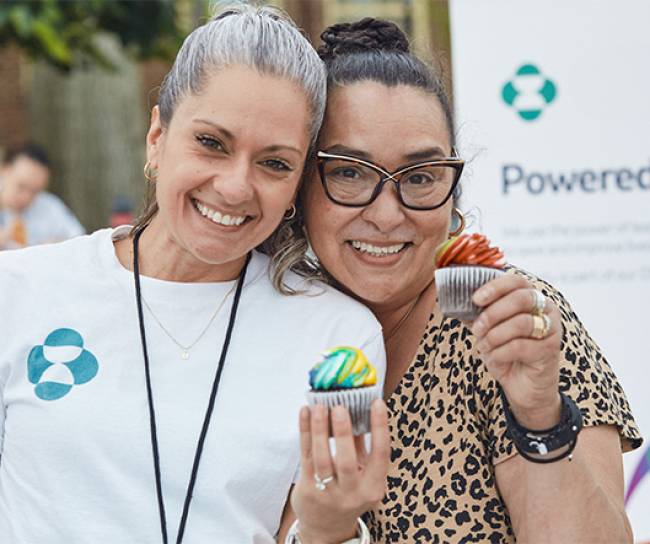two women holding cupcakes and smiling