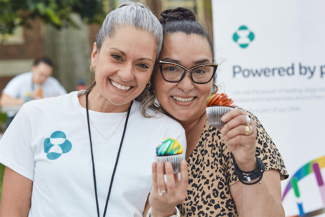 two women holding cupcakes and smiling