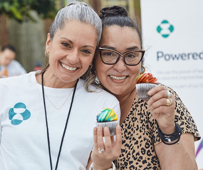 two women holding cupcakes and smiling