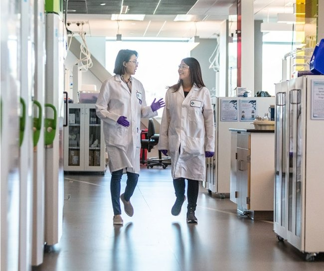 Two female scientists walk and talk in laboratory