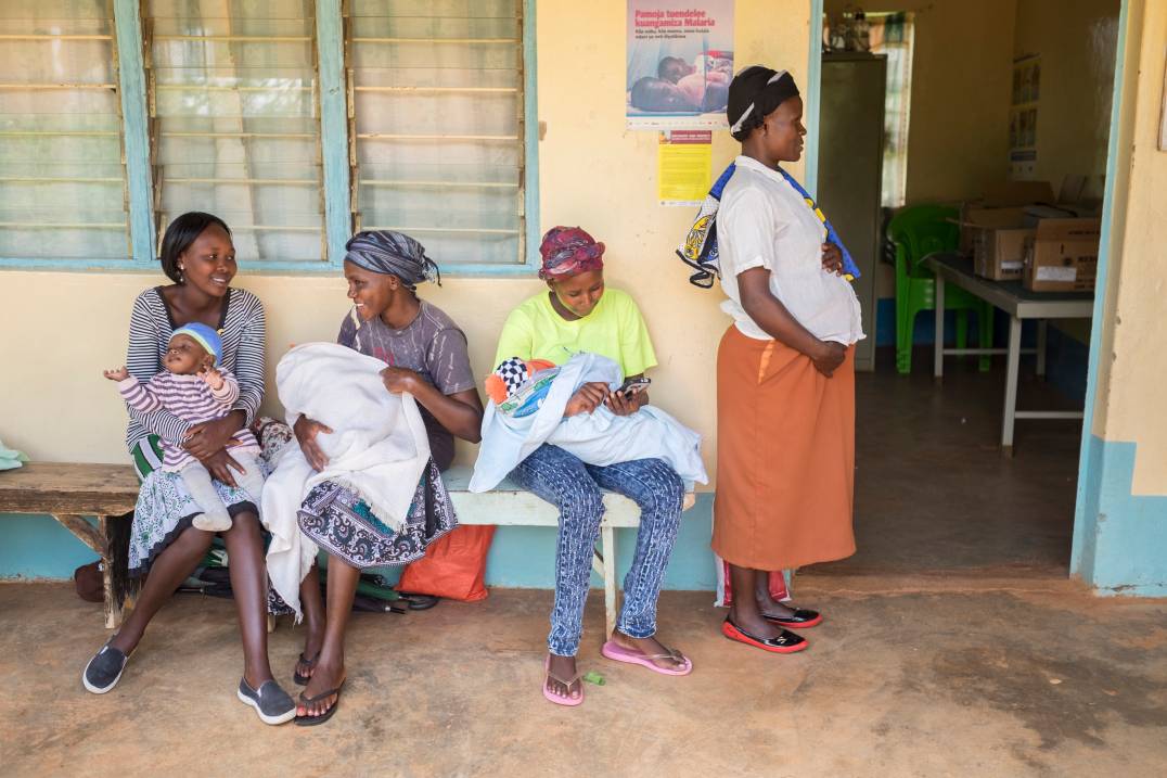 women sitting on bench and holding babies