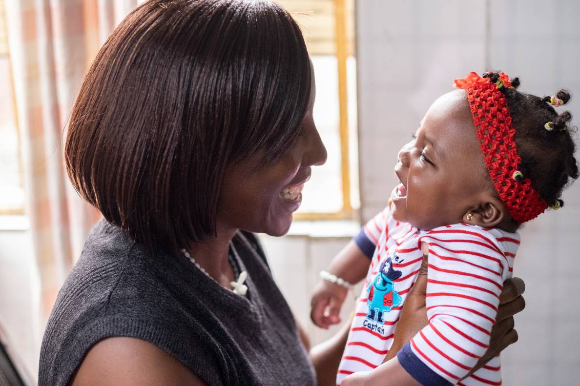 woman smiling and holding a smiling infant