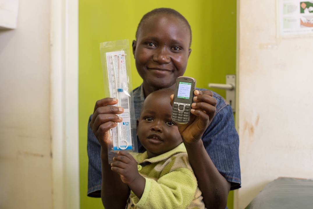 Woman smiling and holding baby and cellphone