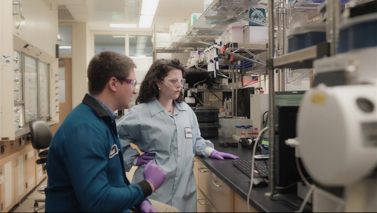 Laboratory scene with individuals in blue lab coats working