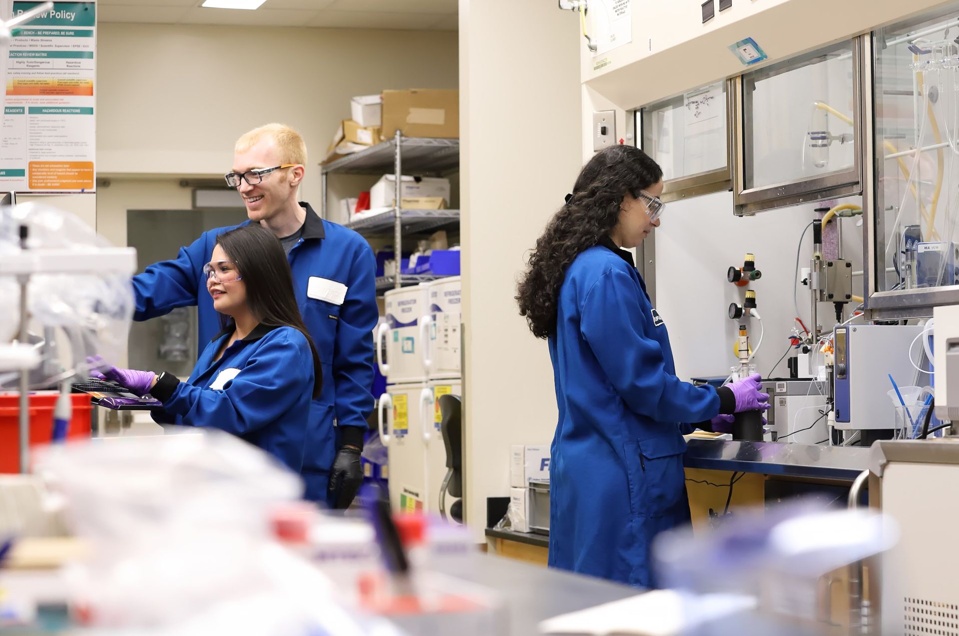 Laboratory scene with individuals in blue lab coats working