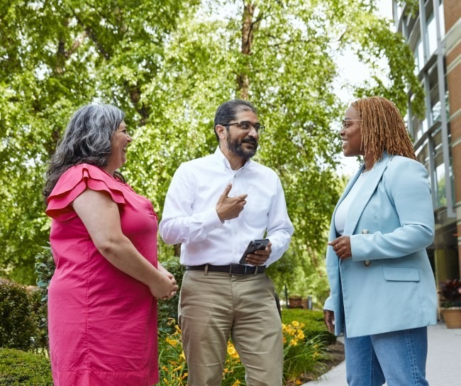 Three employees talking outside the building