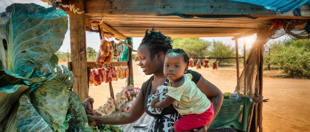 mom holding a baby shopping produce