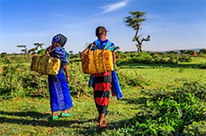 Young girls carrying water walking in nature