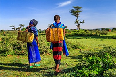 Young girls carrying water walking in nature