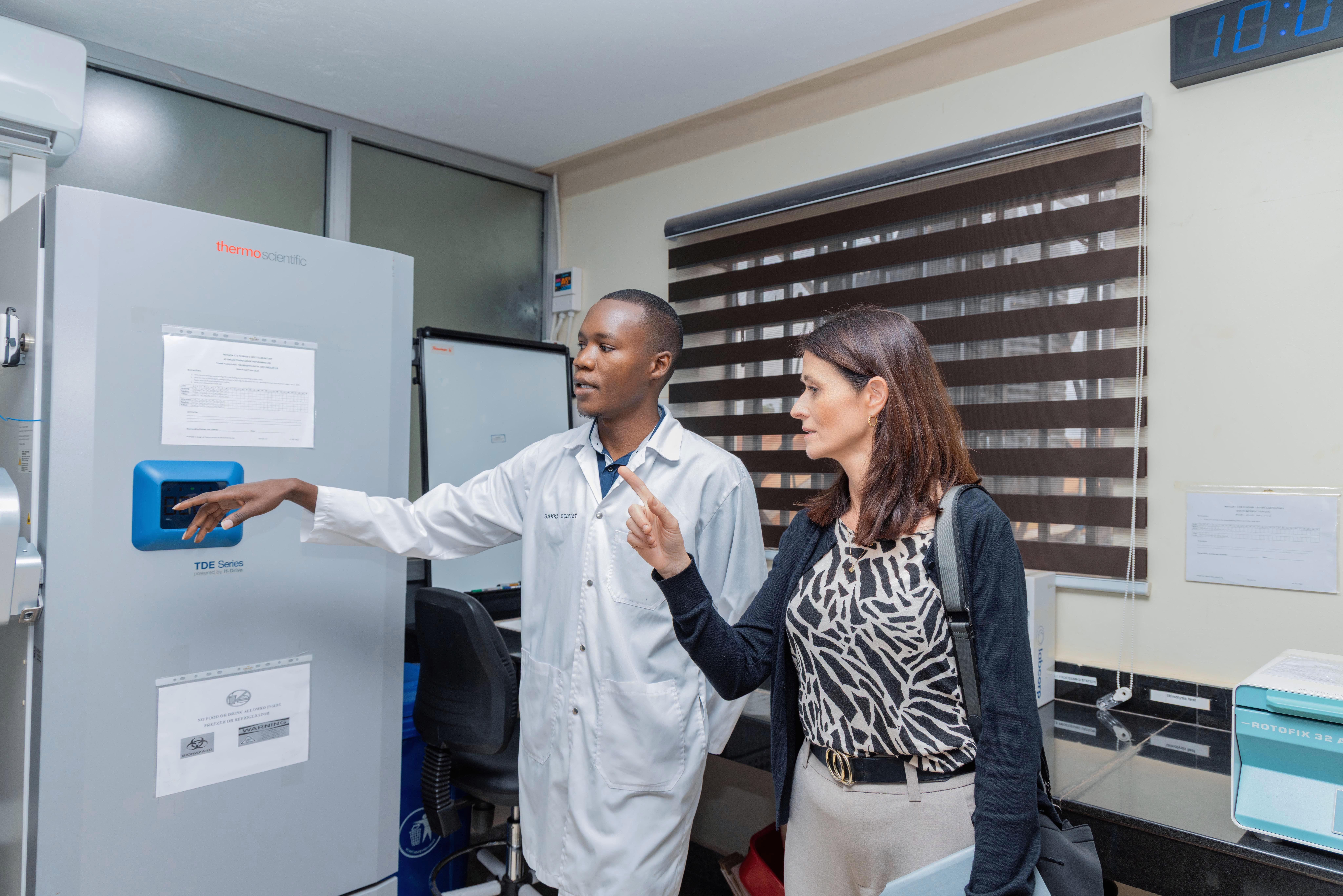 Godfrey Ssaka, laboratory manager at MU-JHU Care Ltd., shows Susan Vaz, a clinical research manager at our company, around the lab.