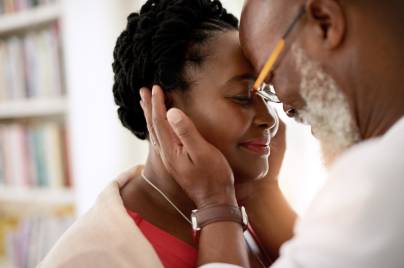 older man gently holding the face of a younger woman