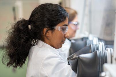 Scientist wearing lab coat and goggles looking in a tube